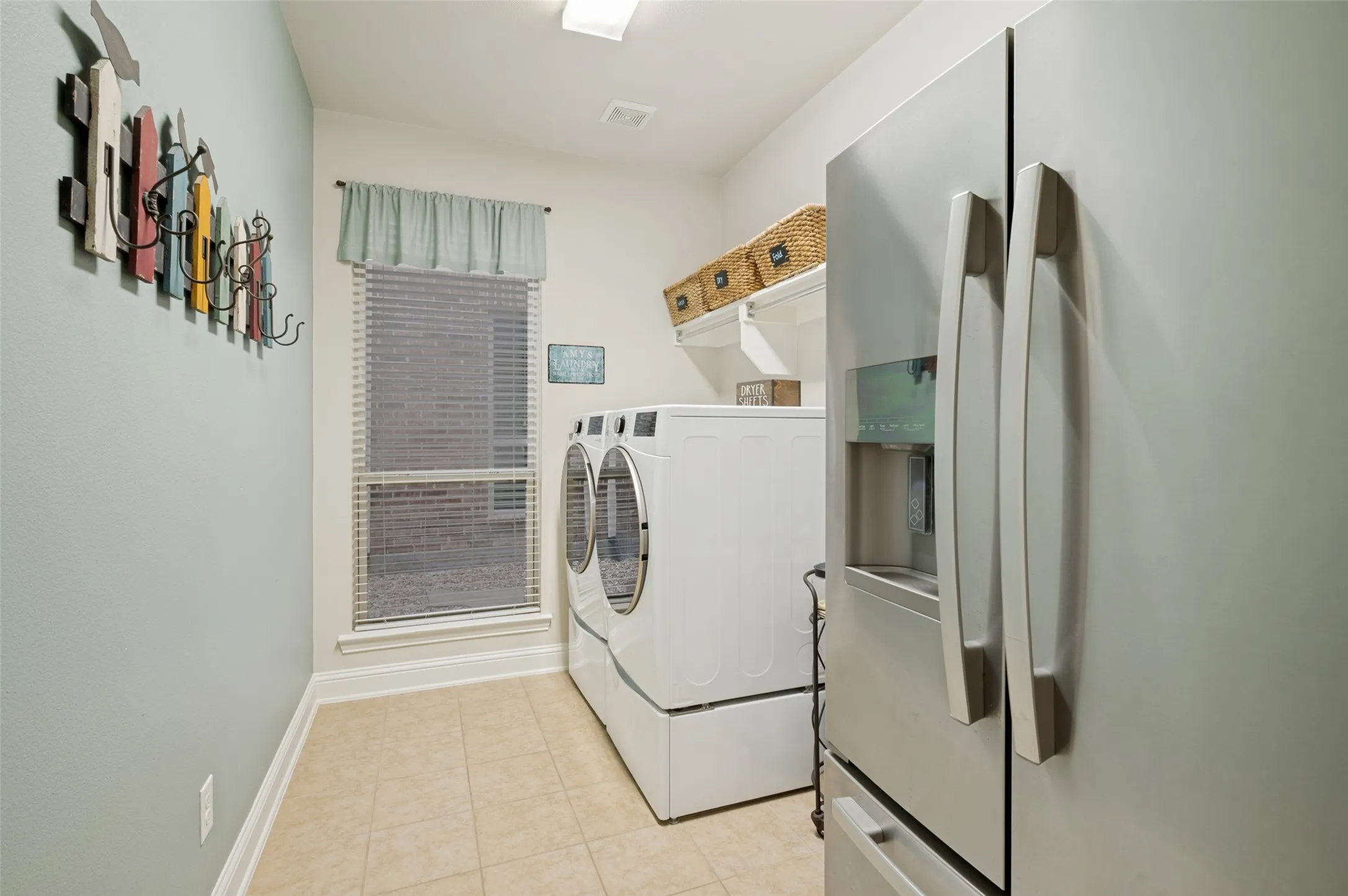 Spacious laundry room with ample storage, upper shelving, and dedicated space for an additional refrigerator or freezer, offering added convenience and functionality for everyday living.