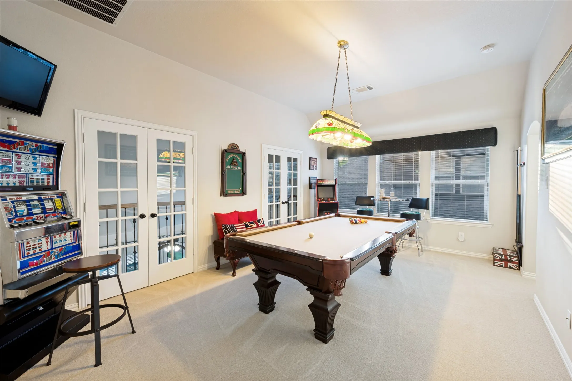 Spacious game room designed for endless entertainment, featuring plenty of room for a pool table, arcade games, and a sitting area. French doors, large windows, and an open layout create the perfect space for game nights, friendly competition, and gathering with family and friends.