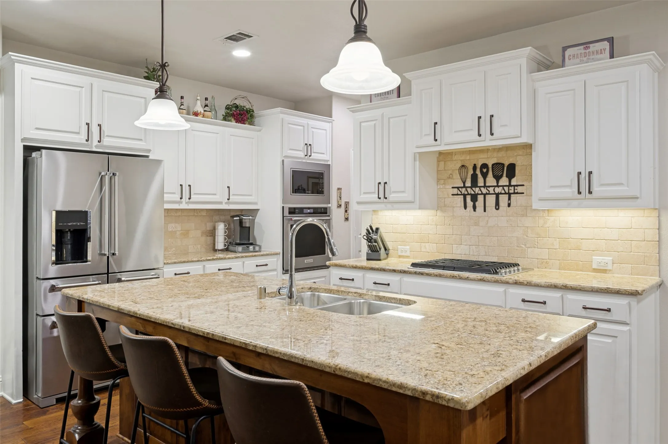 Freshly updated kitchen featuring crisp white cabinetry with new hardware, new stainless steel appliances, and a large center island with seating, all complemented by granite countertops and abundant prep space.