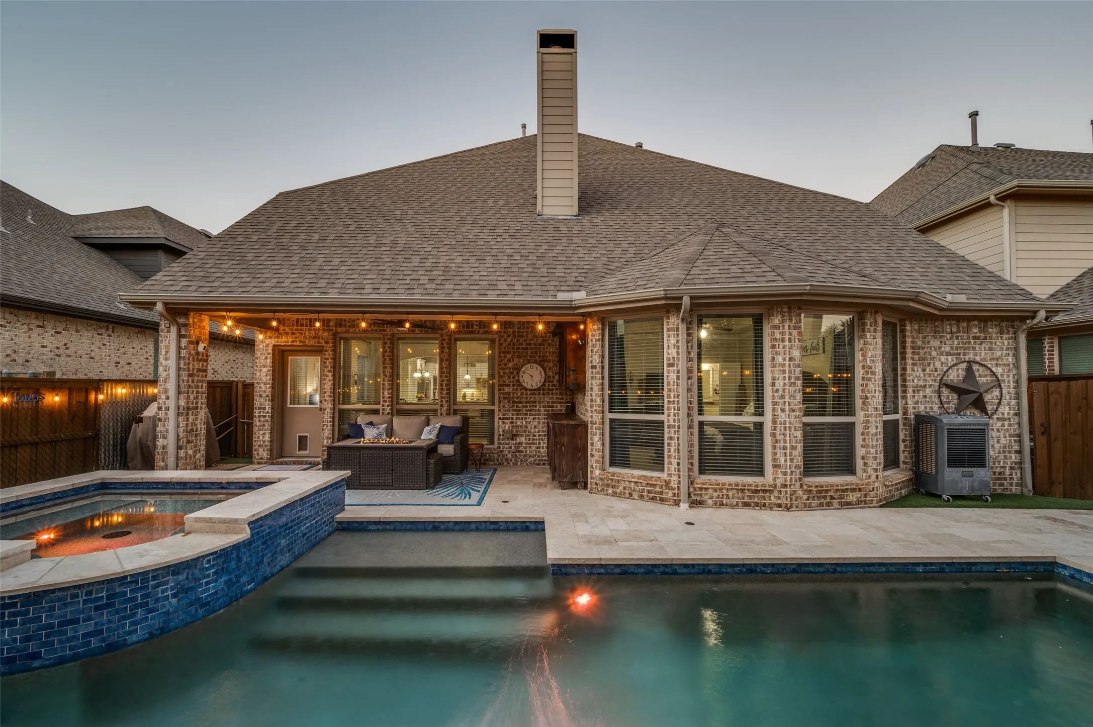 Beautifully designed backyard featuring premium travertine decking, low-maintenance turf, and a sparkling pool with raised spa and tranquil water feature.