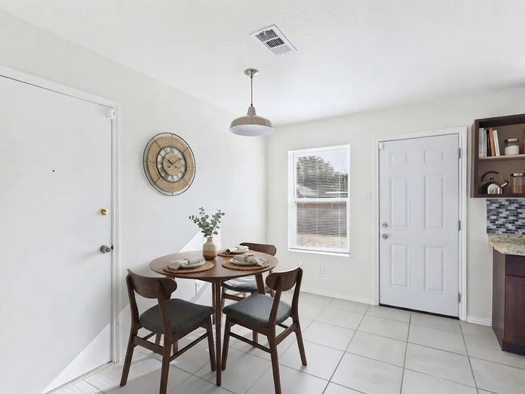 White painted walls with white trim, light-toned tile flooring, single-pane window with blinds, and a built-in dark wood-finish cabinet with open shelving