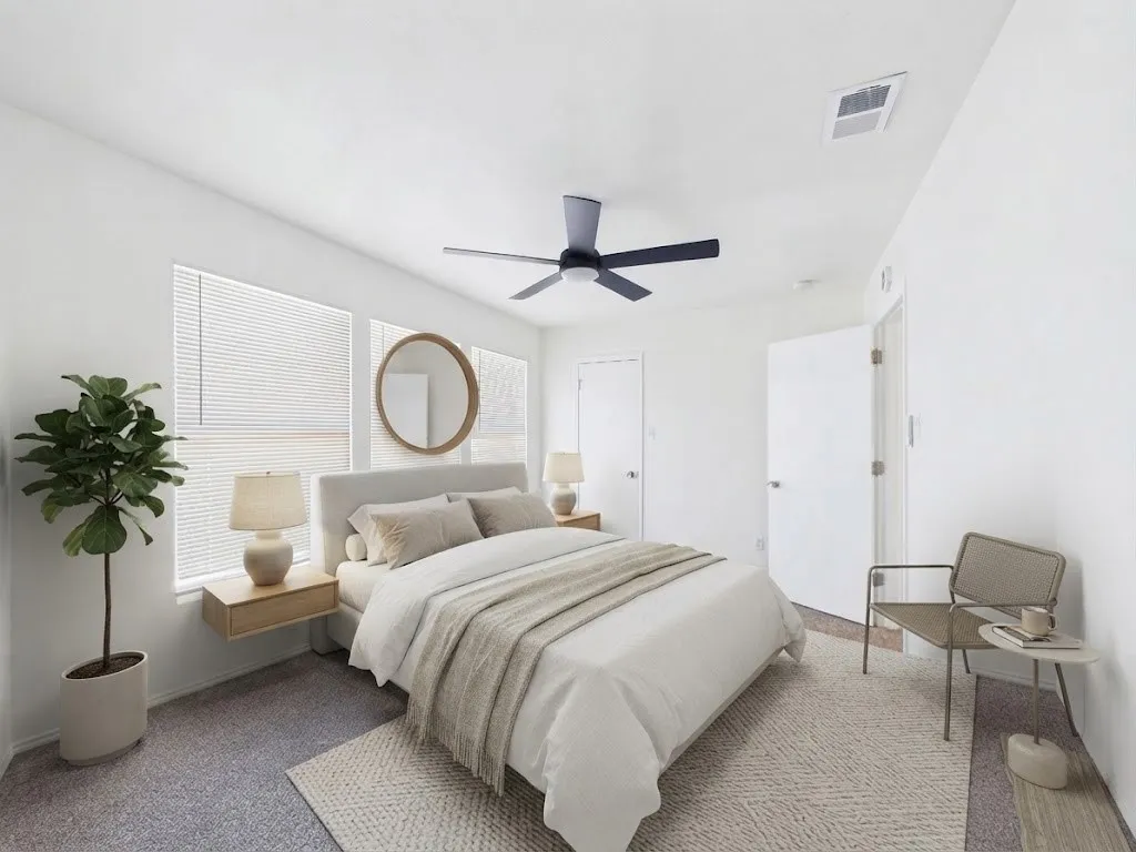 Carpeted flooring, white walls, two windows with blinds, and an overhead ceiling fan