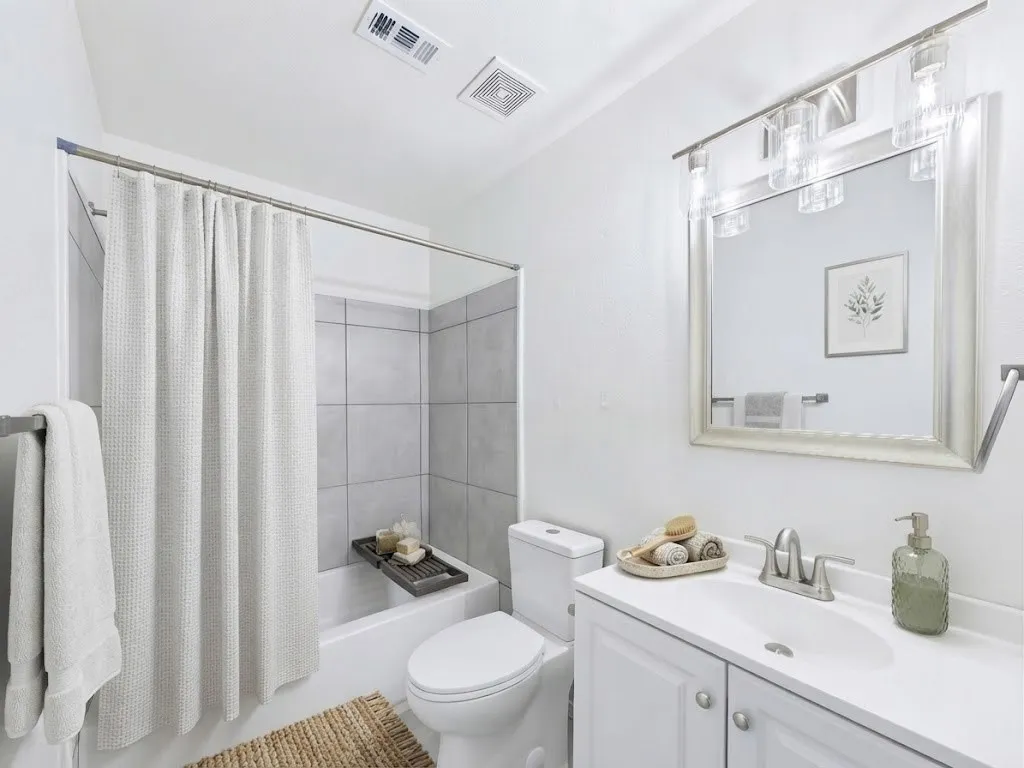 White vanity with undermount sink, brushed nickel faucet, and framed mirror with integrated lighting