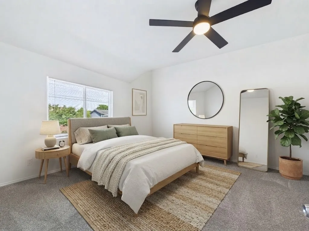 White walls with a vaulted ceiling, gray carpeting, dual pane windows, and a black ceiling fan with integrated lighting