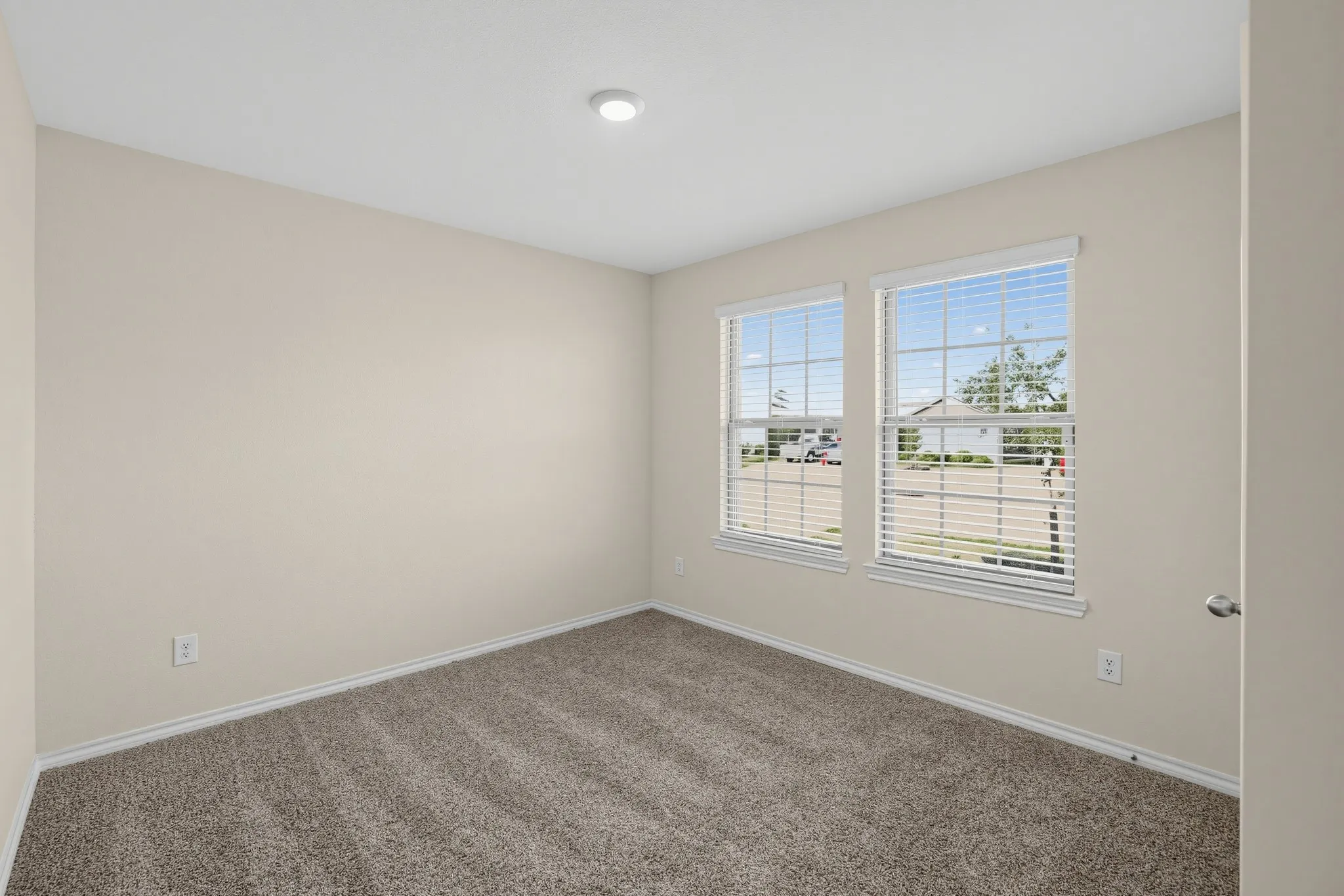 Neutral-toned carpeting, light-colored walls, and two multi-pane windows