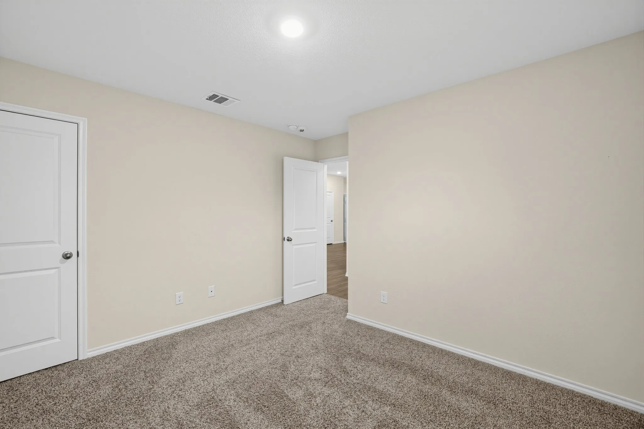 Neutral wall tones, recessed lighting, and soft carpet flooring