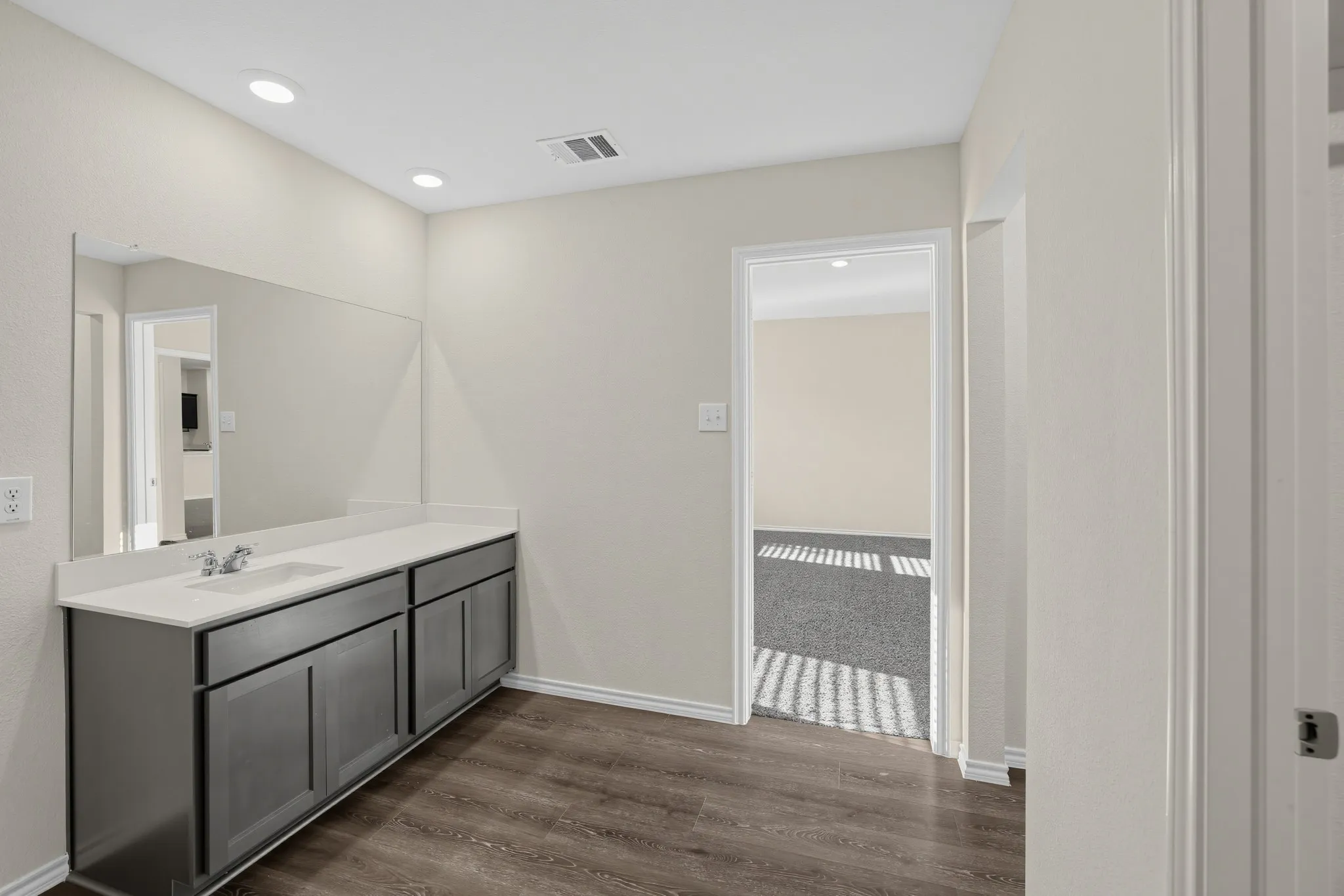 Vanity with light-colored countertop, undermount sink, and dark cabinetry