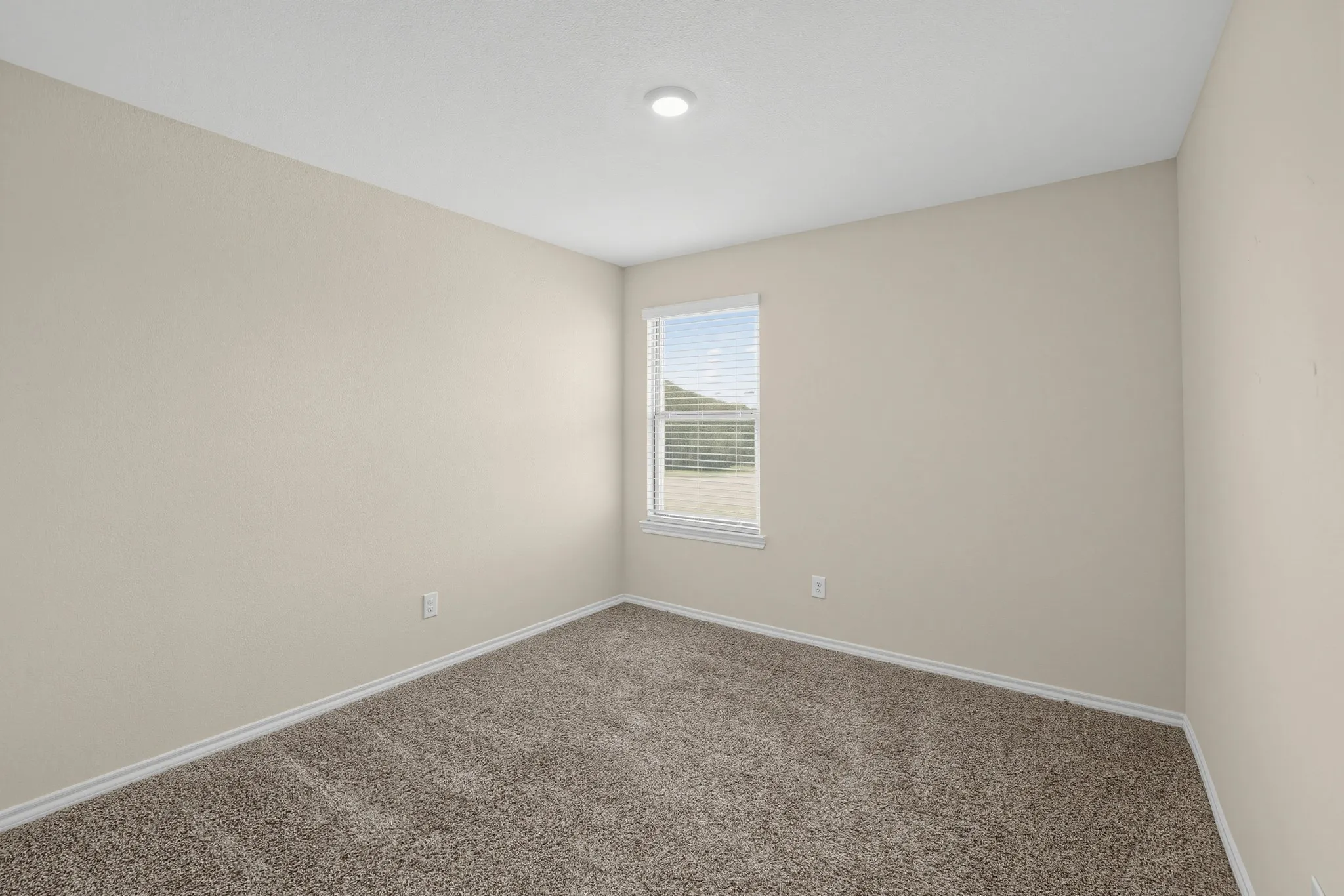 Recessed ceiling lighting, textured neutral walls, window with blinds, and carpeted flooring