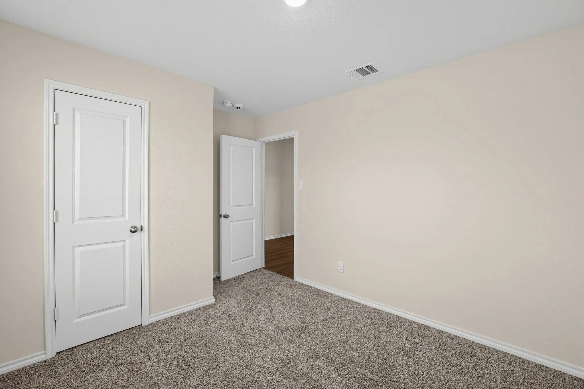 Neutral-toned walls complement the textured carpet flooring