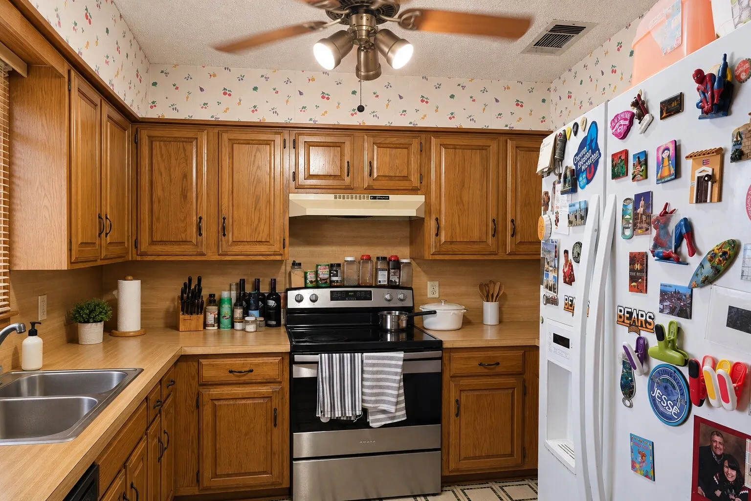 U-shaped kitchen layout with wood-finish cabinetry, a stainless steel range, and a double basin sink