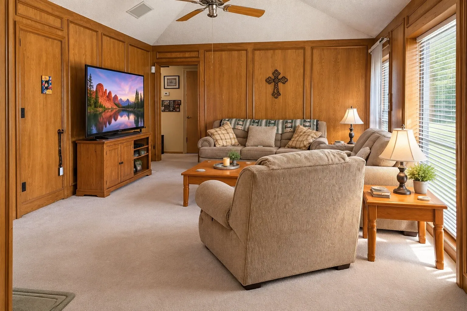 Vaulted ceiling with a ceiling fan, light-colored carpeting, wood-paneled walls, and multiple windows with blinds