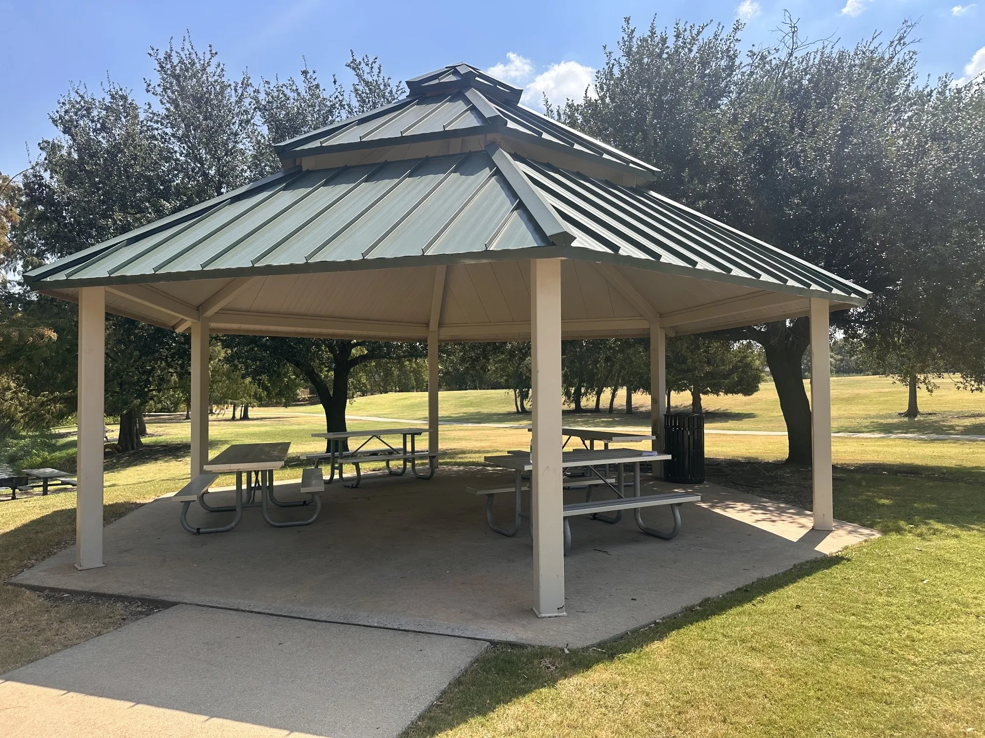 Hexagonal gazebo with a tiered green metal roof and a concrete pad