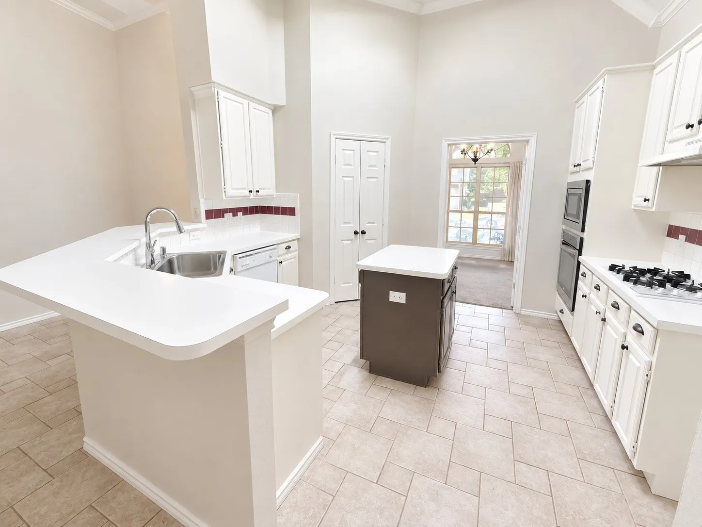 Kitchen featuring a center island, white cabinetry, built-in double oven, gas cooktop, and tile flooring