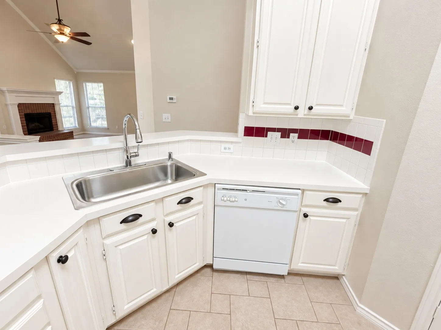 Kitchen featuring white cabinetry, a stainless steel sink, white countertops, and a white dishwasher