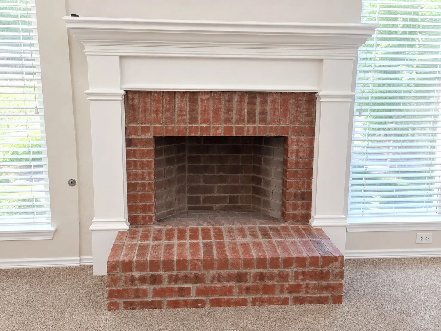 Brick fireplace with a substantial hearth, white mantel, and surrounding trim