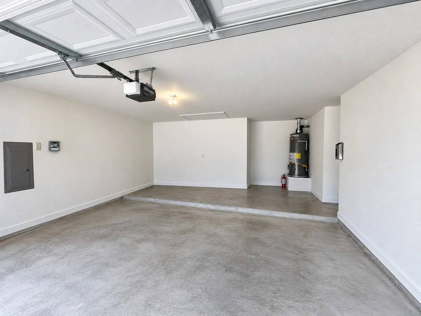 Attached garage with an automatic opener, exposed ceiling beams, and concrete flooring