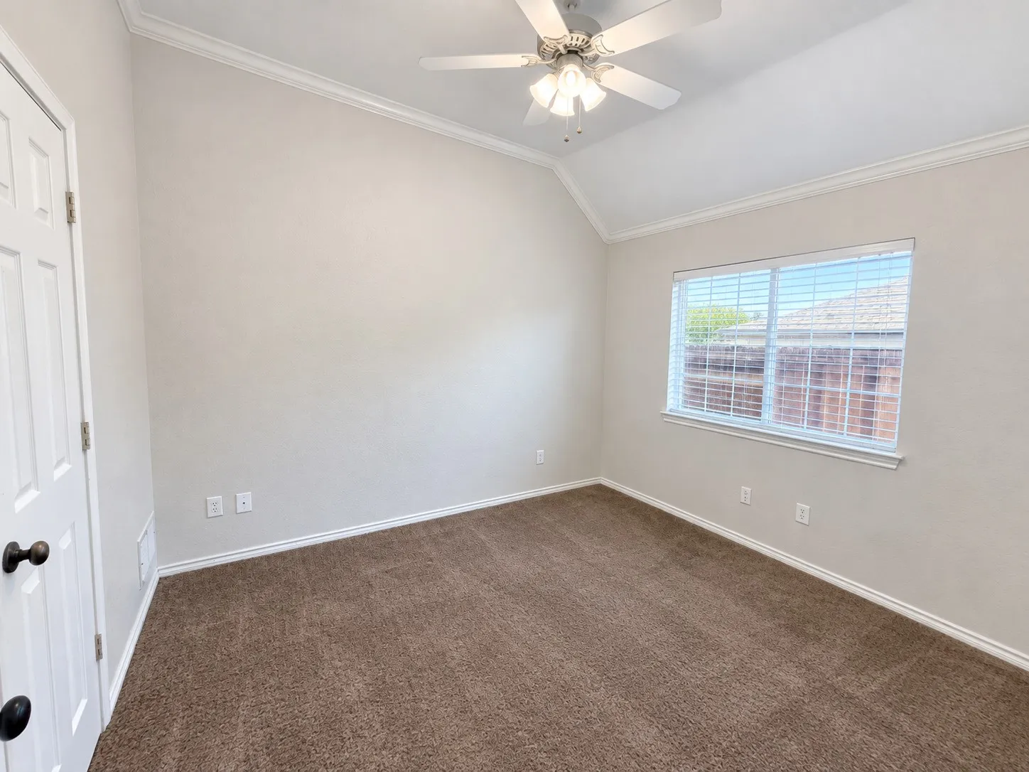 Vaulted ceiling with crown molding, carpeted flooring, and a ceiling fan with light fixture