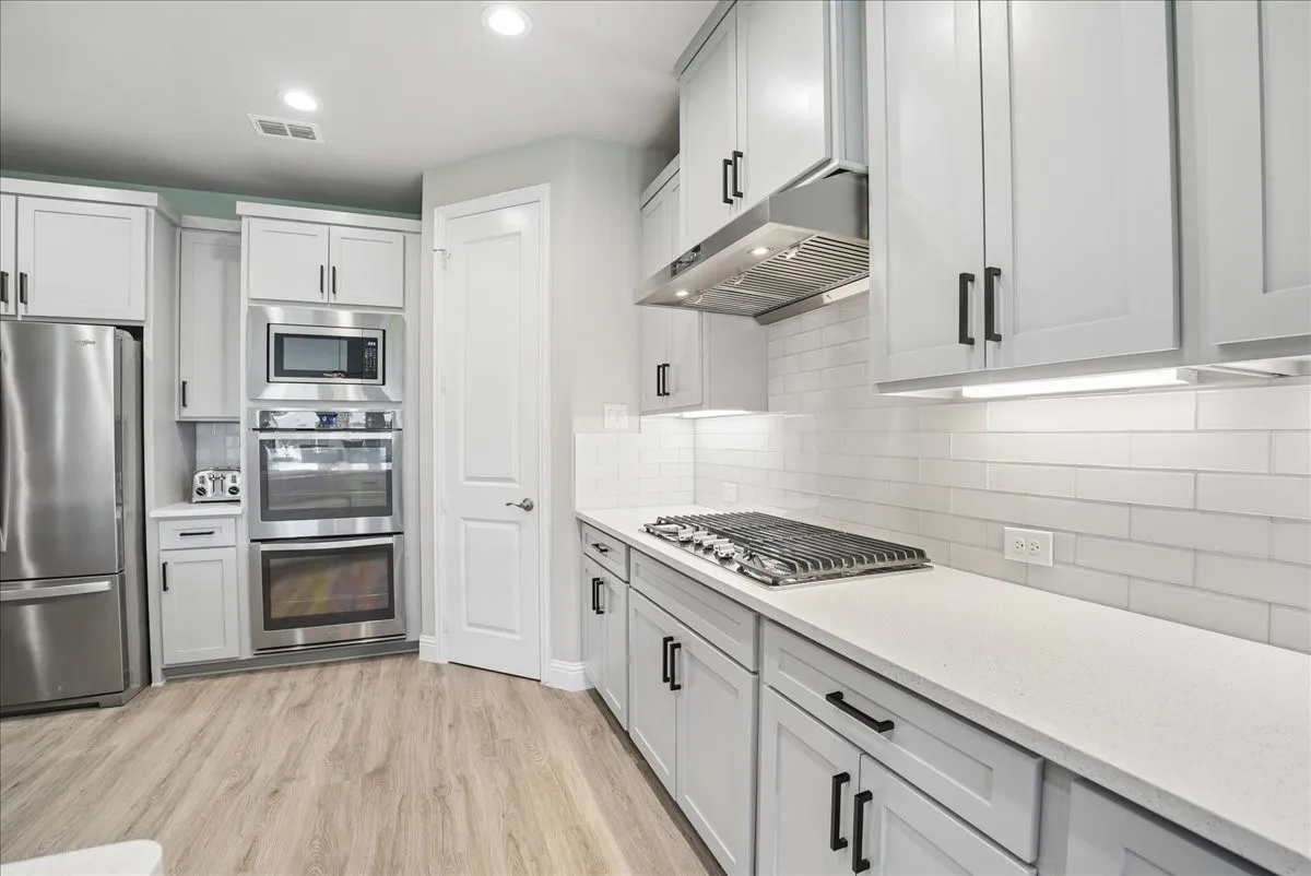 Beautiful kitchen featuring built in gas cooktop, double ovens, quartz countertops and abundant cabinetry.