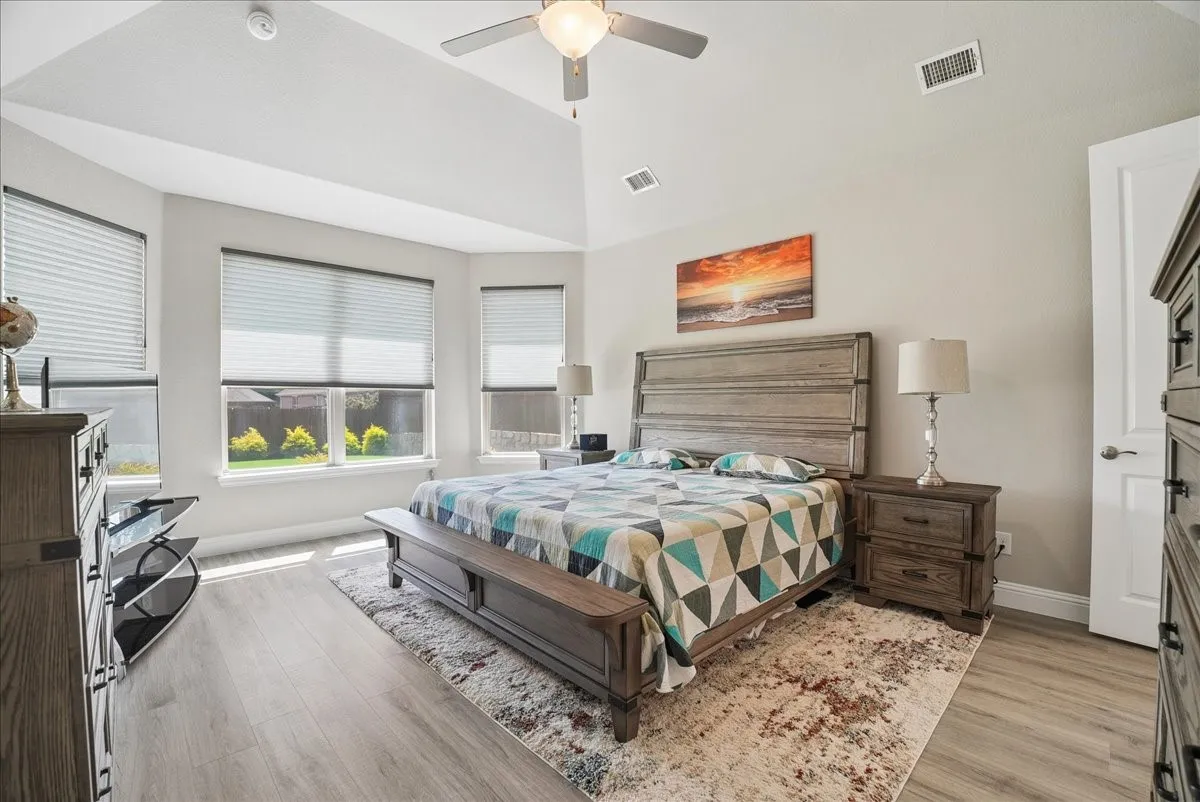 Spacious primary bedroom with vaulted ceiling and abundant natural light.