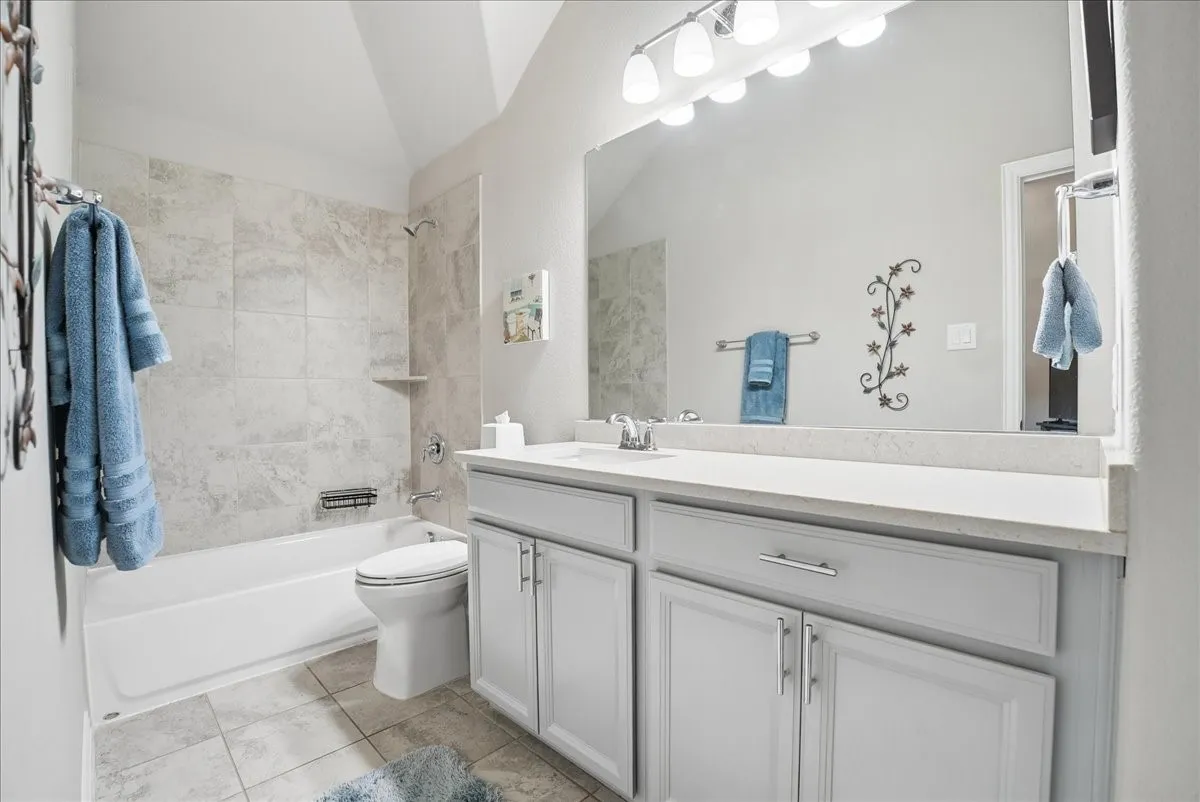 Private en-suite bath featuring spacious vanity and tiled tub/shower combination.
