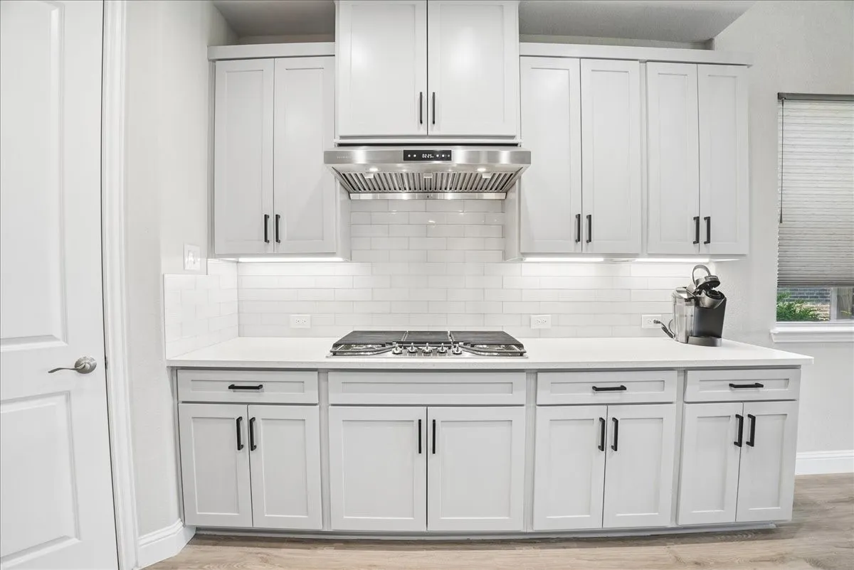Upgraded vent hood, under-cabinet lighting, quartz countertops and stylish backsplash complete this beautiful kitchen.