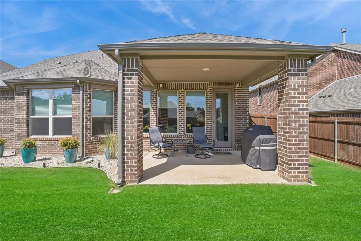 Covered back patio overlooking a beautifully maintained backyard, perfect for outdoor entertaining.