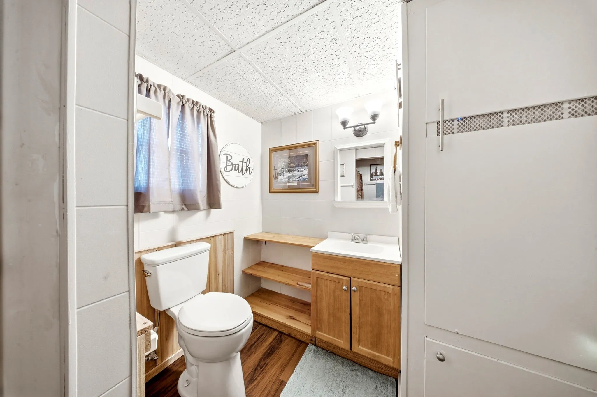 Vanity with wood cabinetry, integrated sink, and wall-mounted mirror