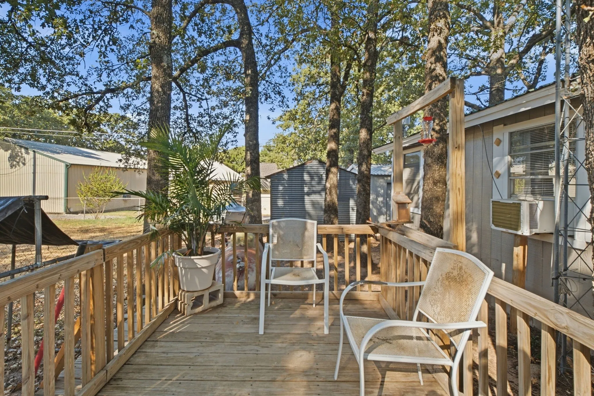 Expansive wood-finish deck with wood railings, surrounded by mature trees