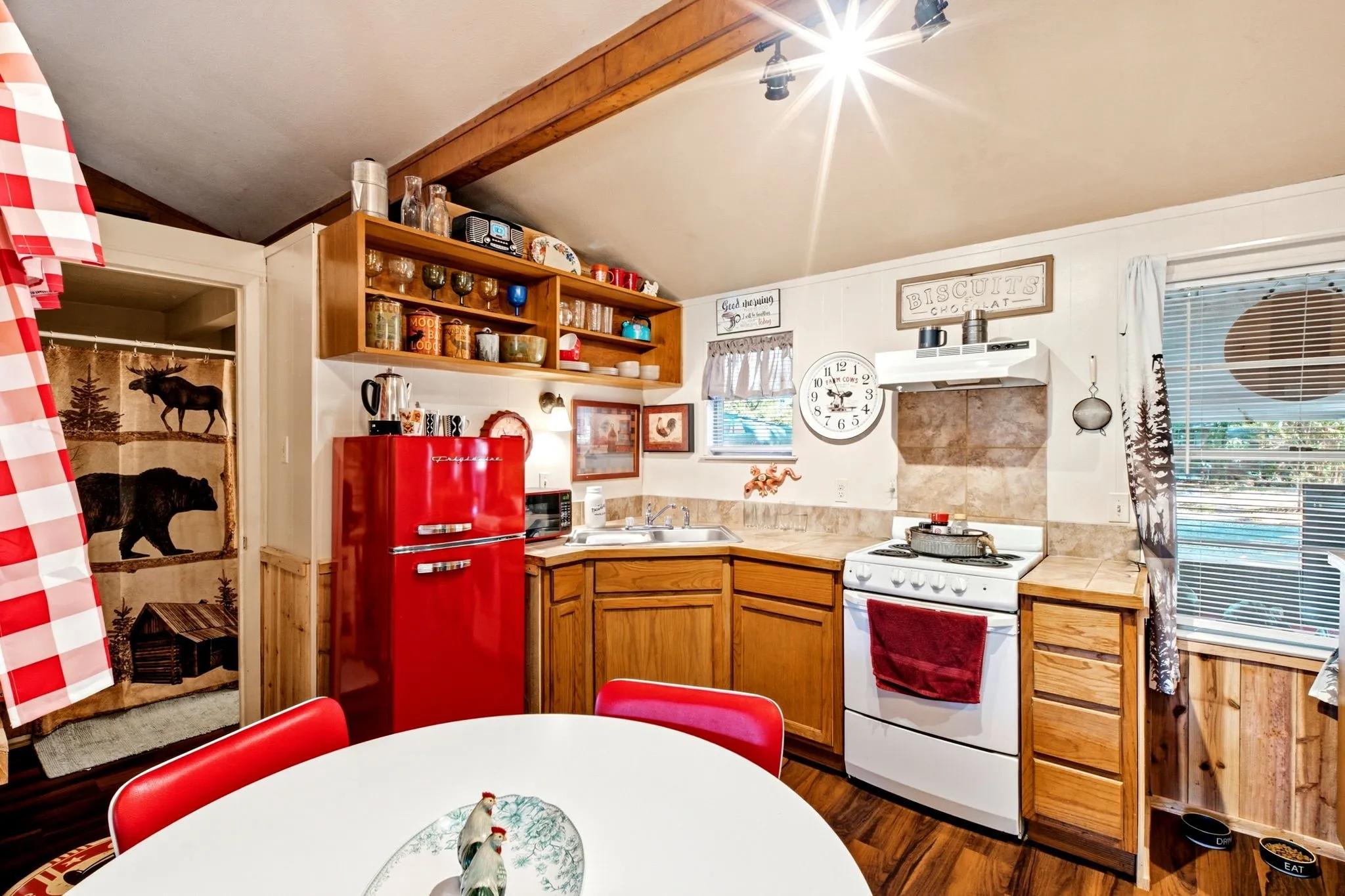 Kitchen featuring wood-finish flooring, wood cabinetry, a built-in range with an overhead exhaust, and open shelving