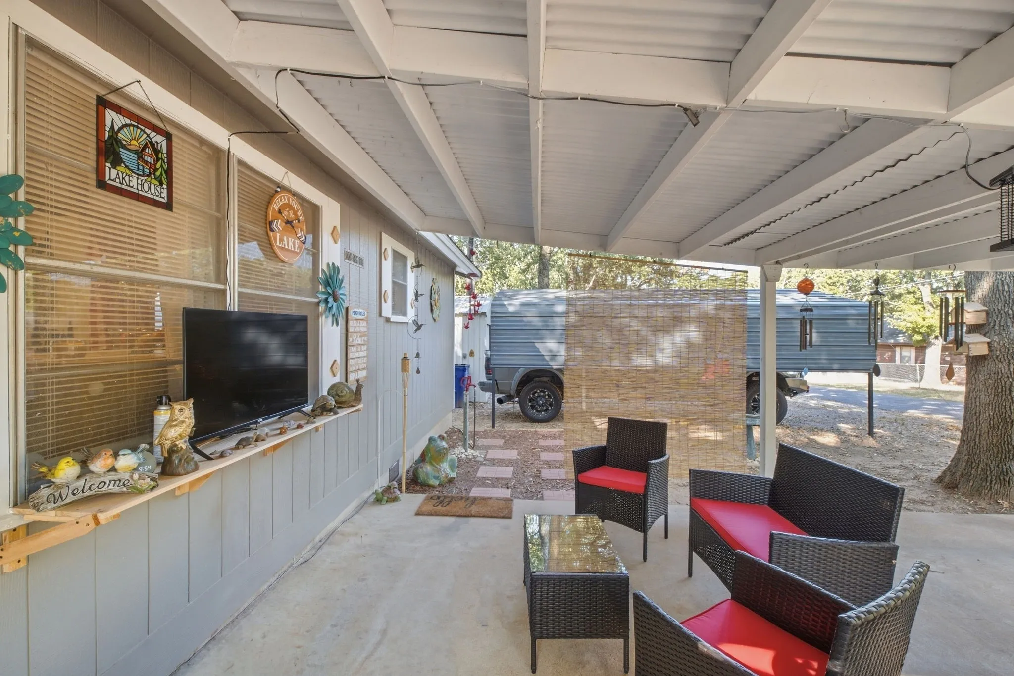 Covered patio with a concrete surface, featuring a window-lined exterior wall and a paver pathway