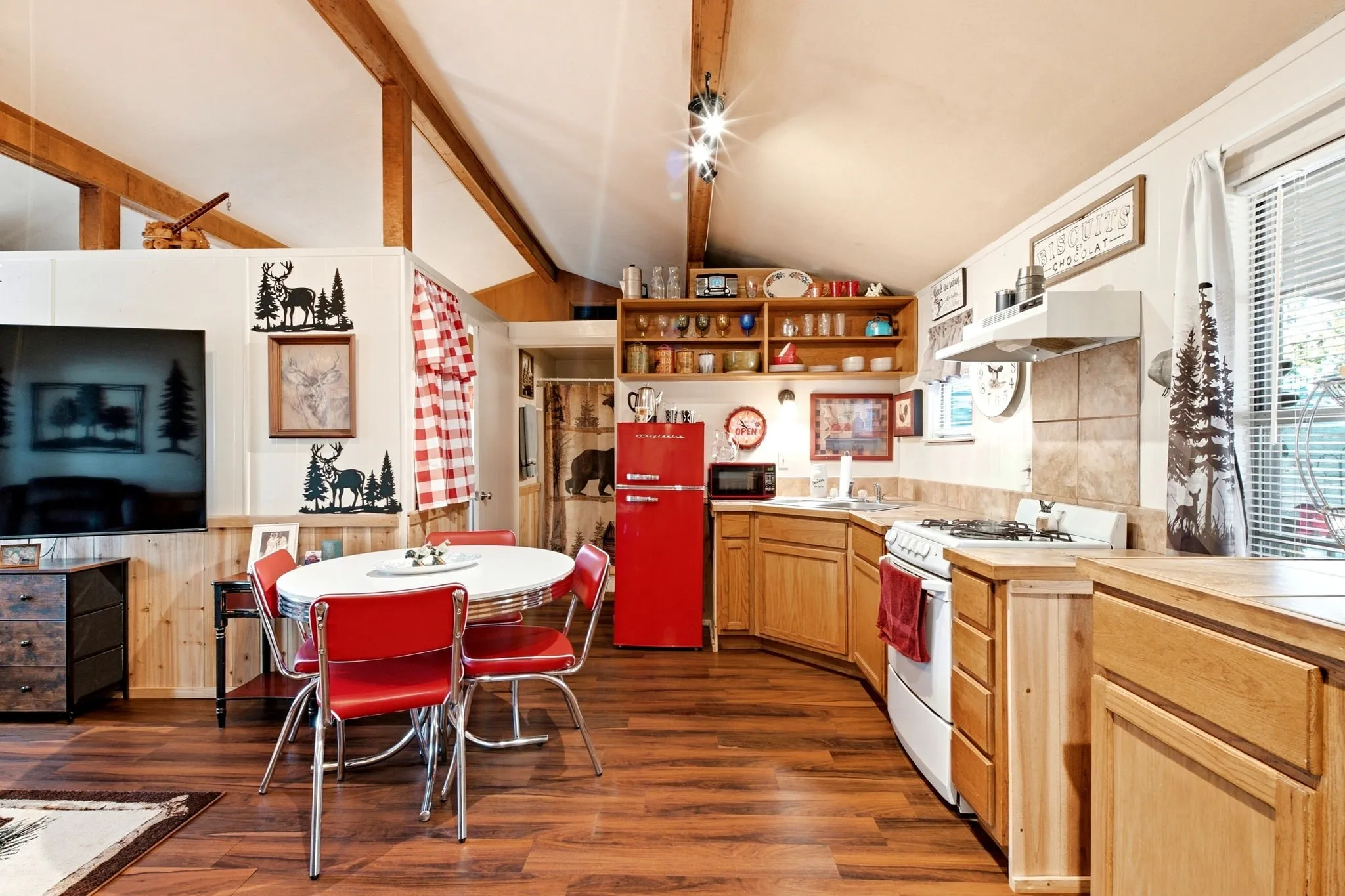 Open-concept interior featuring wood-finish flooring, exposed wood beams, and natural wood cabinetry