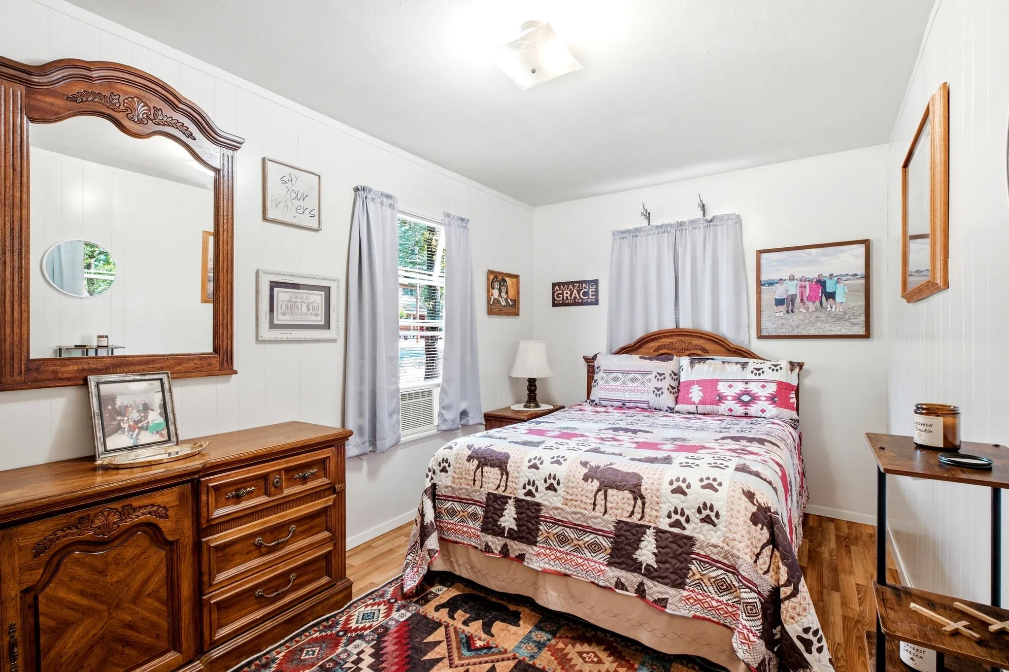 Wood-finish flooring, white paneled walls, and a window with an integrated air conditioning unit