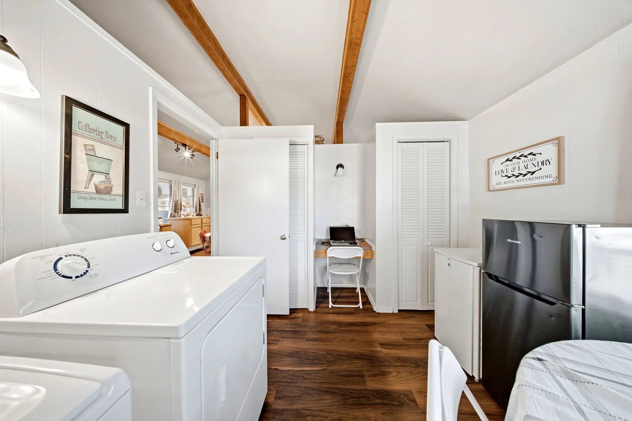 Wood-finish flooring, exposed wood ceiling beams, built-in desk with shelving, and white paneled walls