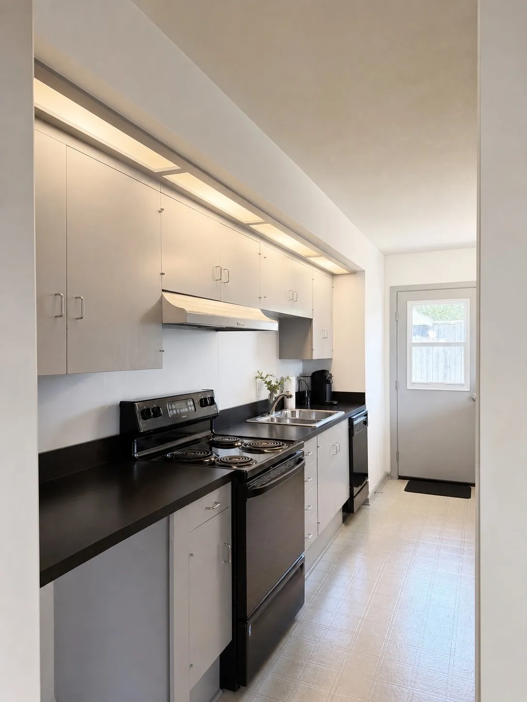 Galley kitchen featuring ample upper and lower cabinetry, dark countertops, a stainless steel sink, and a full-size electric range