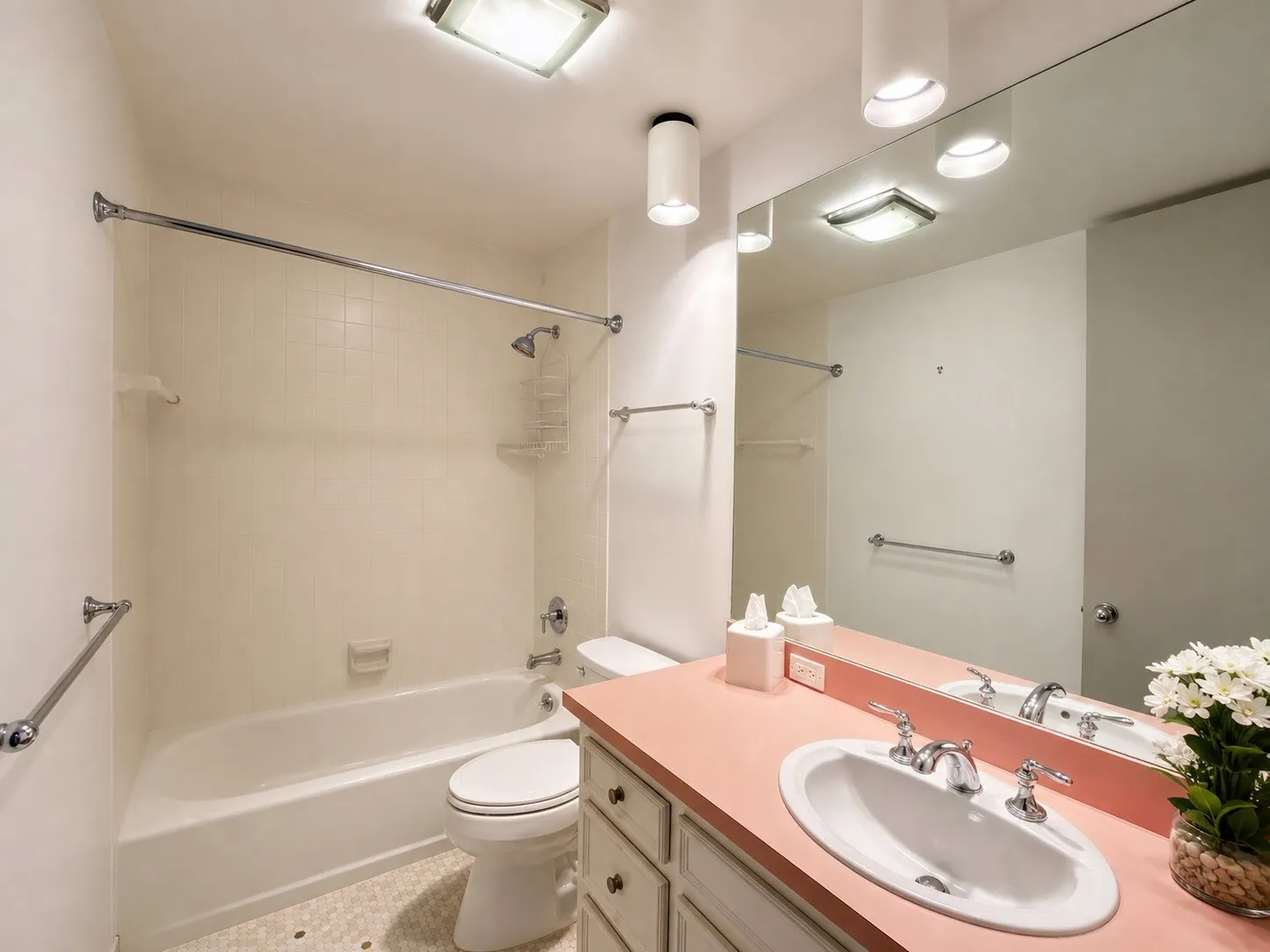 Tub/shower combination with chrome fixtures, vanity with integrated sink, full-width wall mirror, and overhead lighting