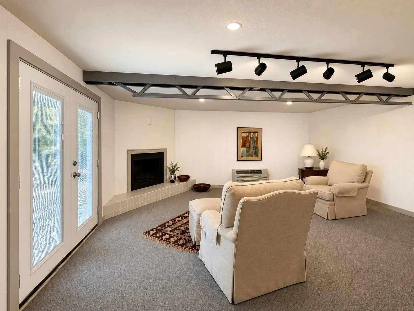 Corner fireplace with tiled hearth, recessed lighting, track lighting, exposed structural beam, and glass-paned double doors