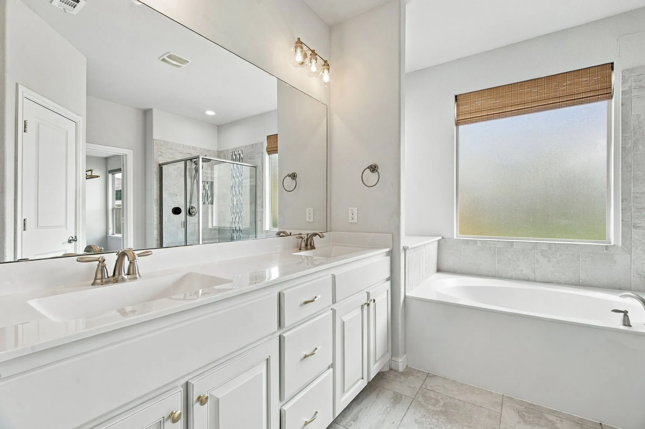 Dual vanity with integrated sinks, brushed nickel fixtures, a built-in tub, tiled shower enclosure, and tiled flooring