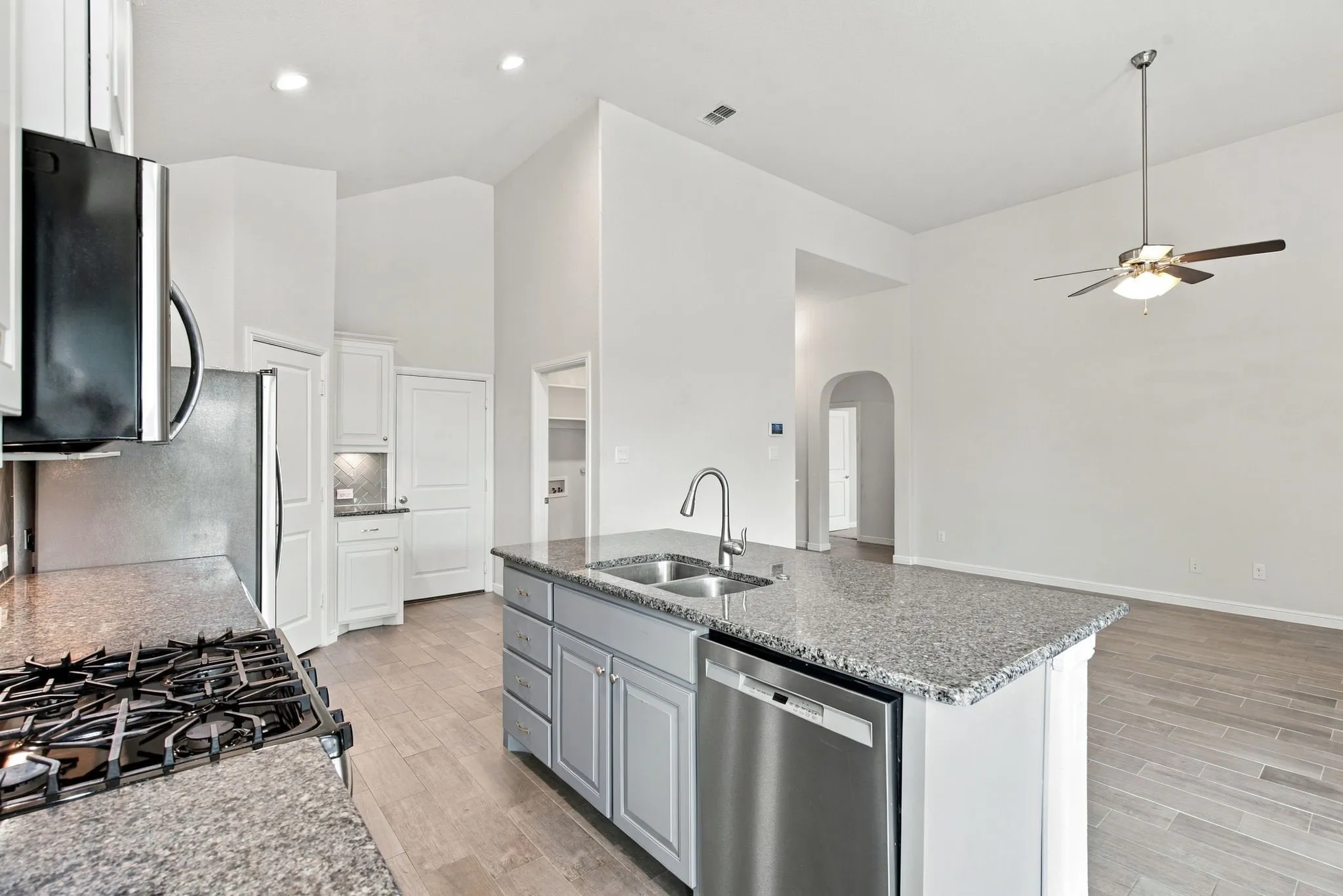 Kitchen island featuring a dual basin sink, stainless steel dishwasher, and granite-look countertop