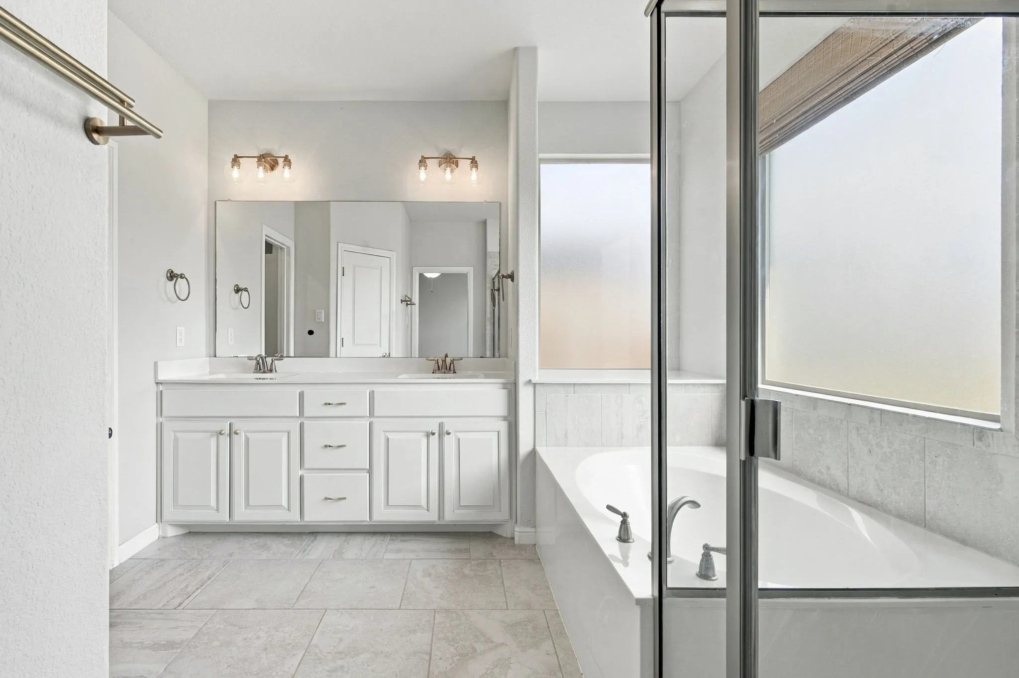 Dual vanity with white cabinetry, a large mirror, and overhead lighting