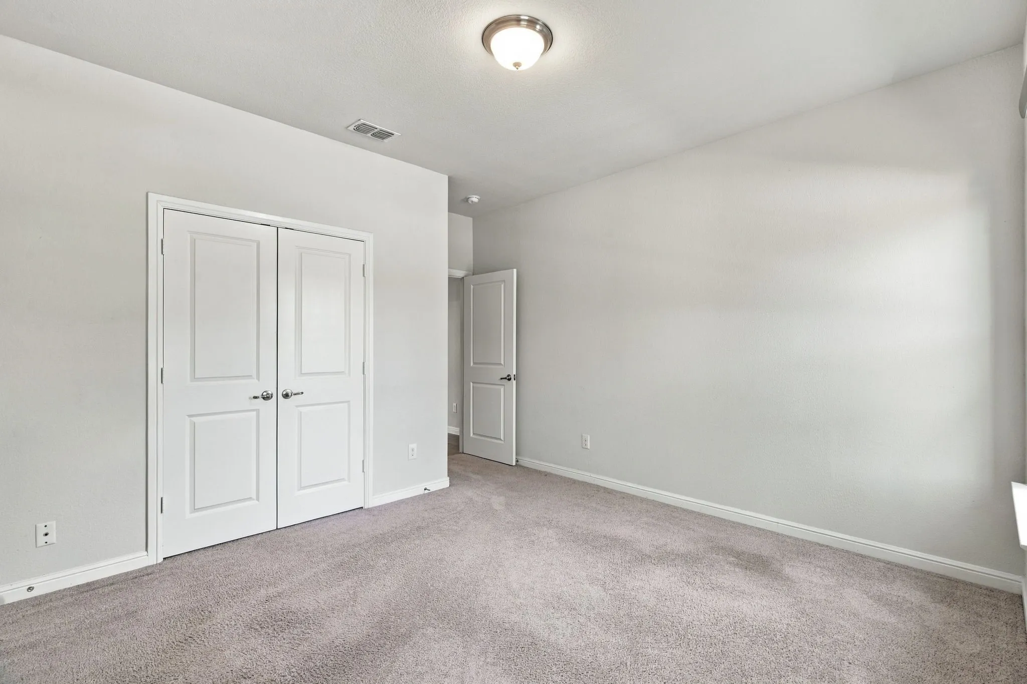 Neutral wall color, light-toned carpet flooring, ceiling-mounted light fixture, white interior doors