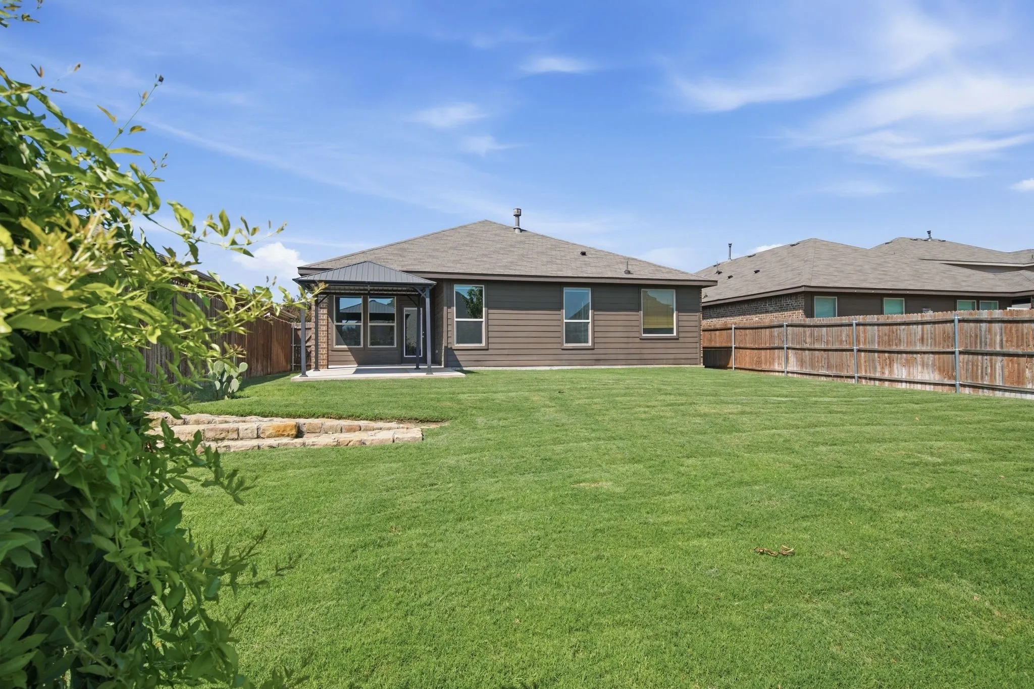 Expansive backyard with a manicured lawn, a covered patio