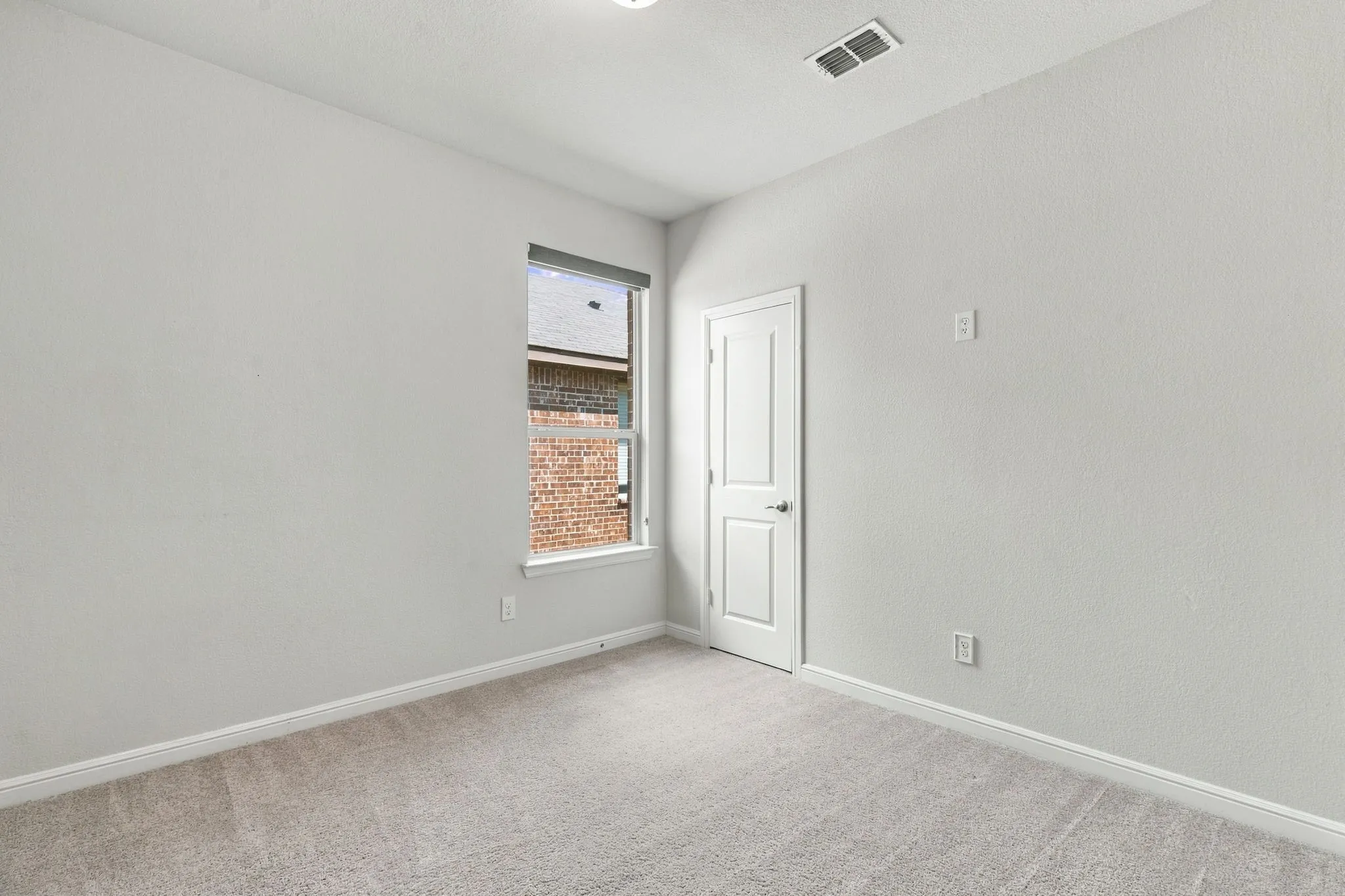 Carpeted flooring, white walls, white trim, single window, and a white interior door
