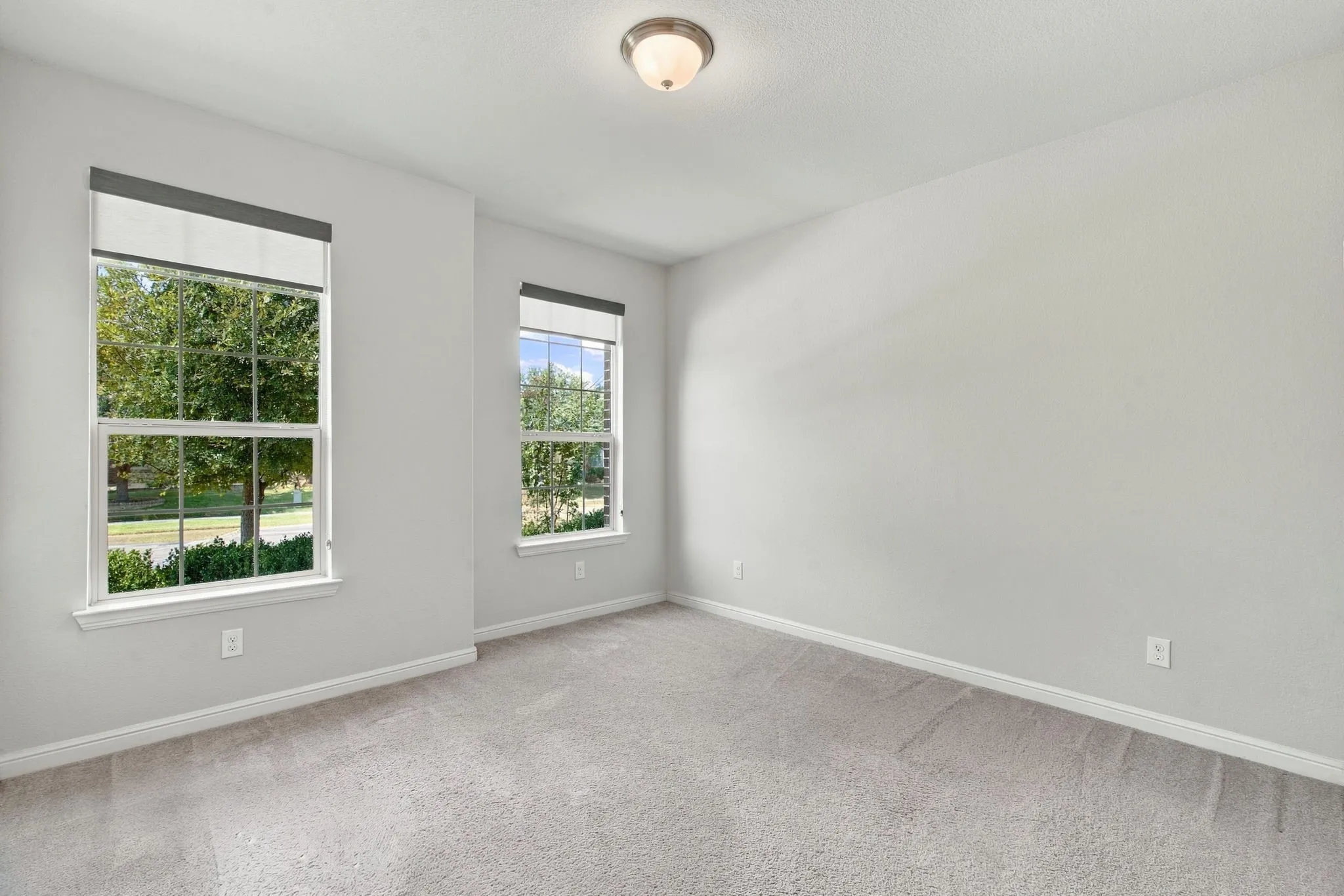 Neutral wall tones, two large windows, and light-toned carpeting
