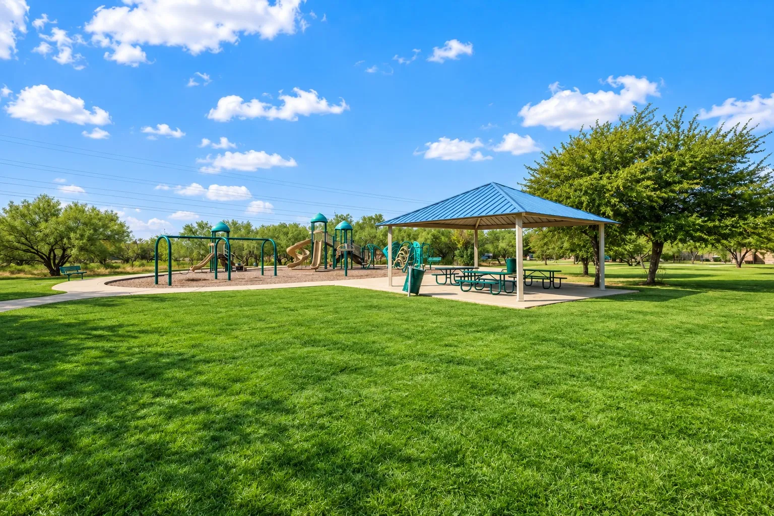 Expansive green space featuring a playground, swing sets, and a covered picnic area
