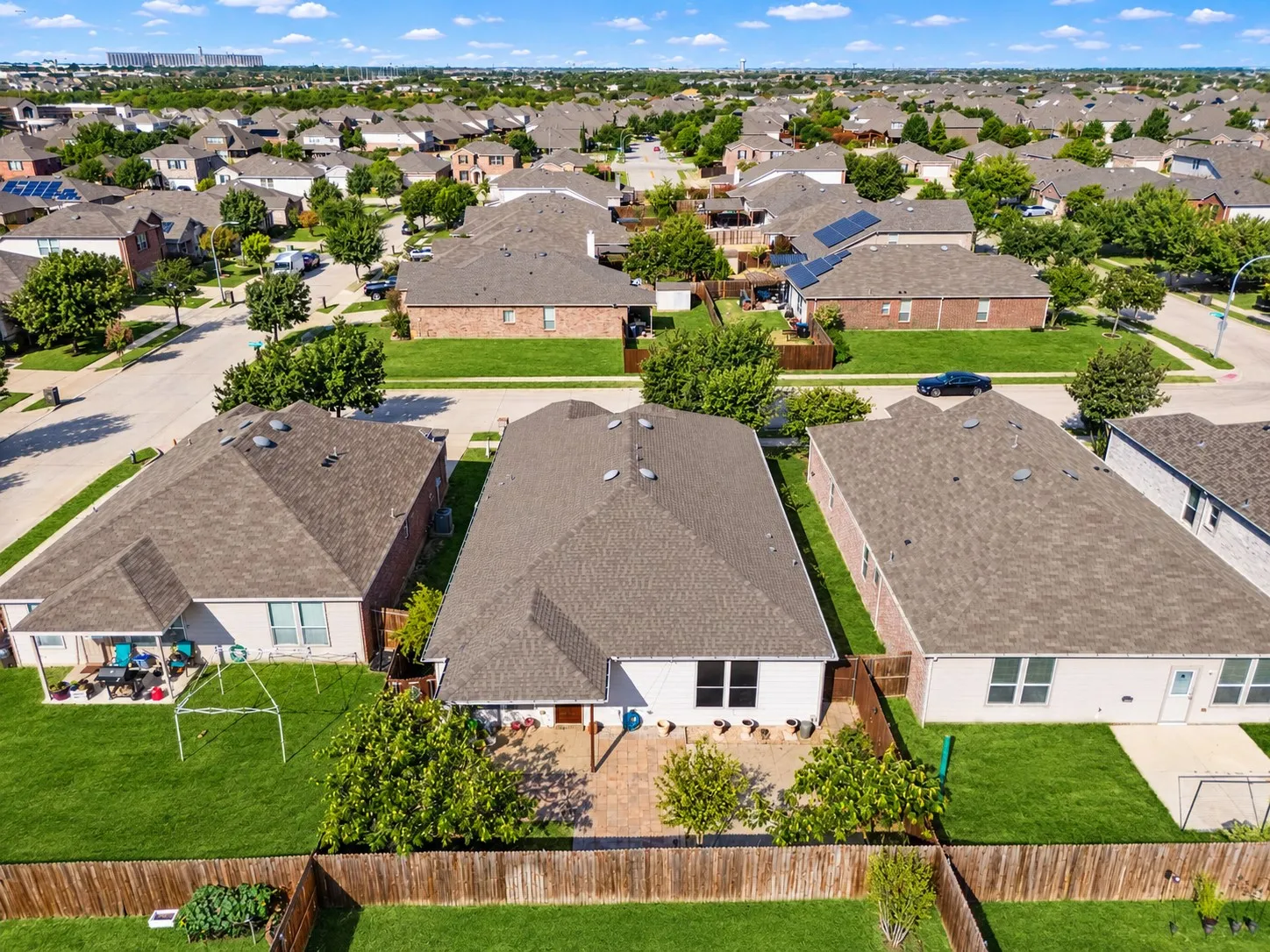 Rear exterior featuring a covered patio, paved patio space, and a fenced yard with mature landscaping