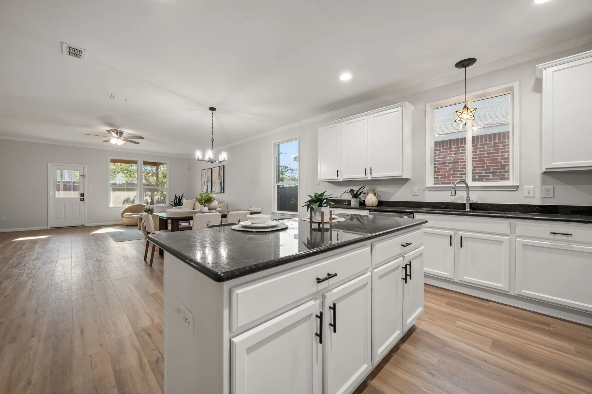 Open-concept kitchen with white cabinetry, dark countertops, and a central island