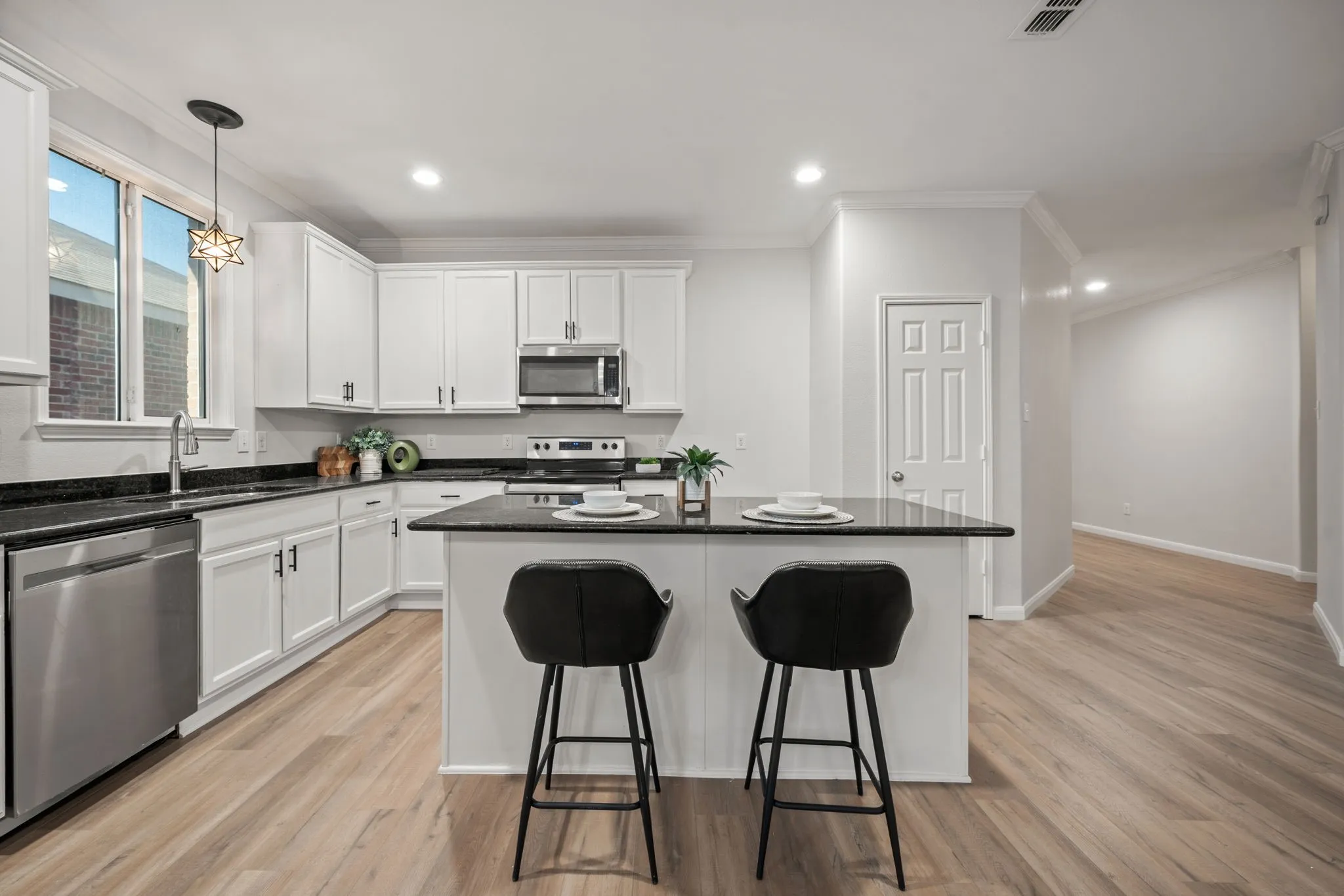 Kitchen featuring white cabinetry, stainless steel appliances, dark countertops, and a center island with seating