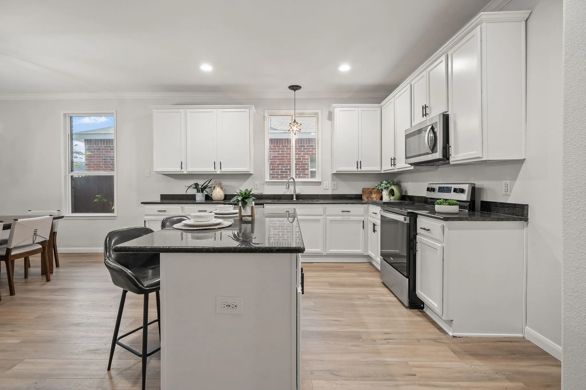 Kitchen featuring white cabinetry, dark countertops, stainless steel appliances, a central island, and wood-finish flooring