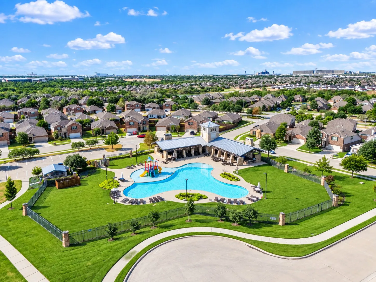 Community swimming pool with a surrounding patio, adjacent covered seating area, and a colorful playground