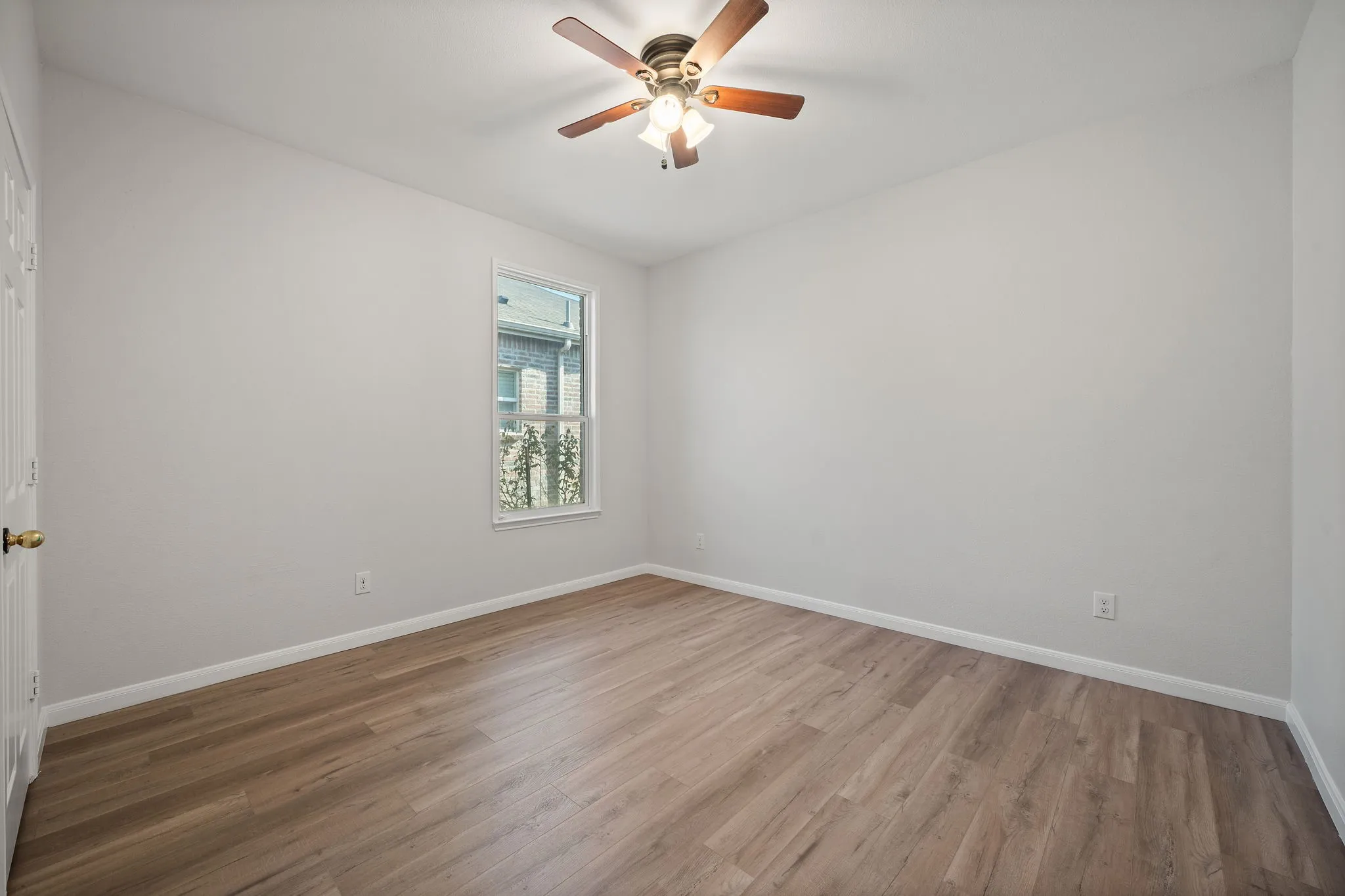 Vaulted ceiling, wood-finish flooring, ceiling fan with integrated lighting, single window, and a white paneled door